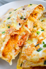 Closeup of Chinese breakfast (Jian Bing) eggy pan cake stuffed with bacon and potato threads.