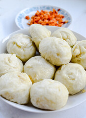 Chinese steamed buns, baozi, a popular breakfast in China. Pickled veggie with red chili blurred at background.