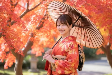 紅葉を背景に鮮やかな和装の女性が和傘を持ち笑顔で立っている