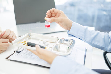 Fototapeta premium A woman is handing a tray of medical supplies to another woman. The tray contains a pen, a bottle, and a pair of scissors. The scene suggests a medical setting 