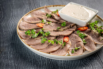Boiled beef tongue with horseradish sauce and greens