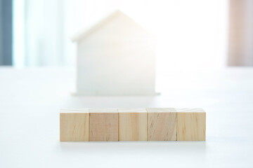 Empty wooden blocks for text and sunlit house background. Home loan business concept.