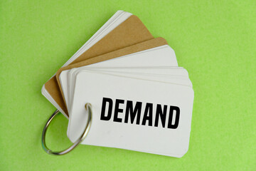 letters of the alphabet with DEMAND words written on white notebook on green background. 