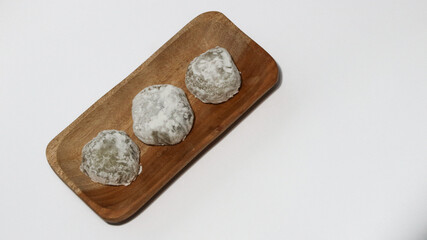 Mochi, a sweet dessert or rice cake filled with chocolate or mung beans, and coated with sesame seeds Mochi cake on a plate with a white background.