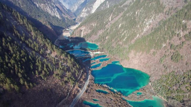 Drone view of Jiuzhaigou National Park in spring in Sichuan Province China. It features cascading waterfalls, turquoise blue lakes, and stunning mountain valleys. 4K real time footage travel concept.