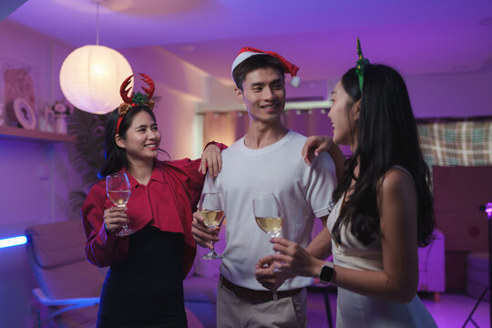 Young friends celebrating christmas party drinking wine