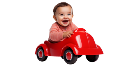 A happy baby in a pink sweater driving a bright red toy car with black wheels on a black background
