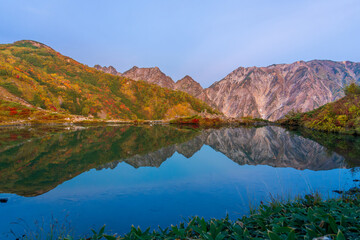夜明けの八方池に映る紅葉の白馬三山