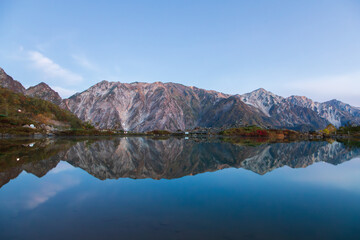 夜明けの八方池に映る紅葉の白馬三山