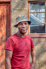 single african man portrait, in the village, standing in front of the house, rural life in...
