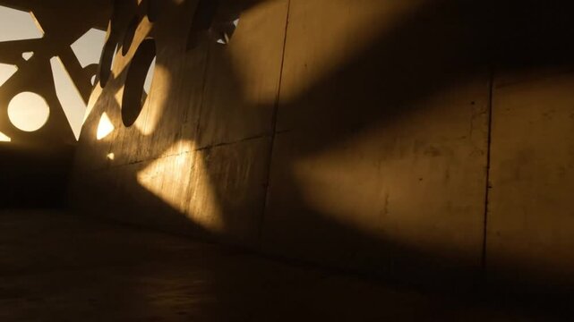 Abstract pattern of light and shadow cast on a textured concrete wall inside space