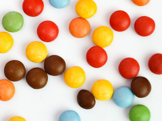 Colorful candy coated chocolate gems forming a vibrant border on white background