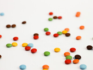 Colorful candy coated chocolate gems forming a vibrant border on white background