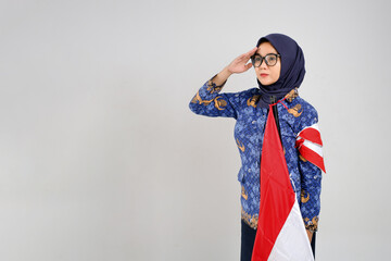 Indonesian beautiful woman in blue batik civil servant uniform giving a salute while holding the...