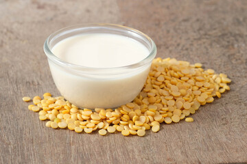 Soy milk in a glass cup and halved soybeans on a wooden table. Healthy food concept.