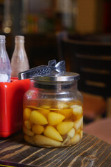 Pickled fruits in jar on wooden table at restaurant