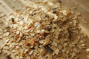 Dry oats with fruit pieces on wooden surface