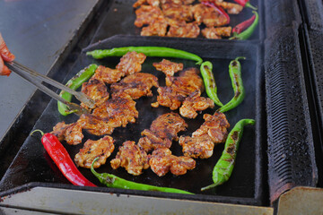 Juicy chicken grilling with vibrant peppers at a food stall