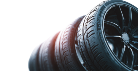 Close-up of stacked car tires and rims.  Dark, textured rubber tires with intricate metal rims are prominently displayed.  A slight gradient effect highlights the tires, creating depth