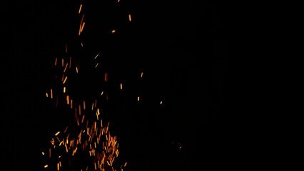 sparks and embers from campfire flying over black background