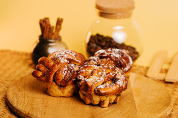 Delicious cinnamon buns displayed on a wooden board with warm colors and coffee accents