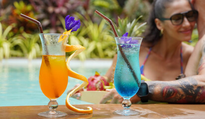 A man and woman with cocktails in a swimming pool
