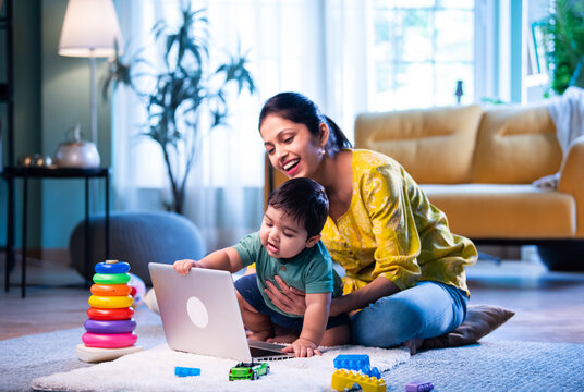 Indian Mother working from home while irritated infant closes laptop, demanding playful attention