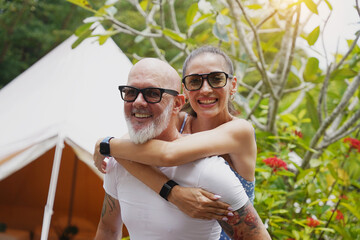 A man and a woman embrace and have a fun in front of a large tent.