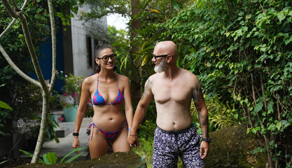 A man and a woman joyfully walking in front of a beautiful pool