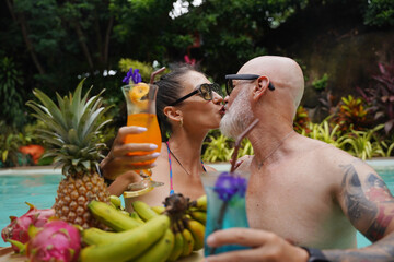 A man and a woman are having fun and drinking cocktails in the pool.