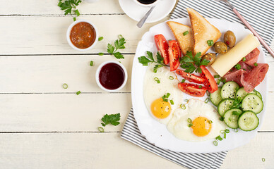 English breakfast - fried egg, salami, cheese, tomatoes, cucumbers and toast. Top view