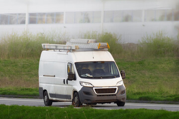 Commercial van driving on road with equipment and supplies
