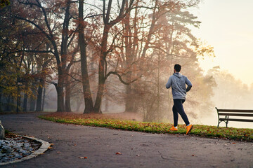Man running in a foggy autumn morning in park
