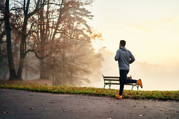 Man jogging on a foggy autumn morning in park