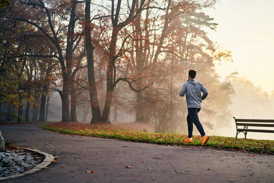 Man running in a foggy autumn morning in park