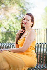 Woman in yellow dress sitting on bench outdoors and smiling