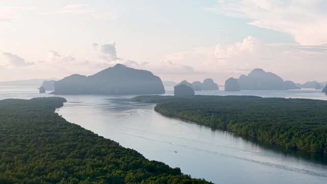 A picturesque aerial shot showcases the natural beauty of the land. A tranquil river flows gracefully through a vast, flourishing forest, eventually meeting the calm, glistening sea under a soft.