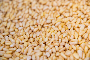 close-up of shelled pine nuts, viewed from above. The background consists of a large number of pine seeds, a healthy, natural, organic food and a product of natural origin