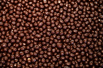 large quantity of chocolate-covered hazelnuts or raisins, the photo can be used as a background. Chocolate-covered nuts make a beautiful, shiny, sugary snack