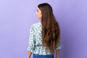 Young caucasian woman isolated on blue background in back position and looking side