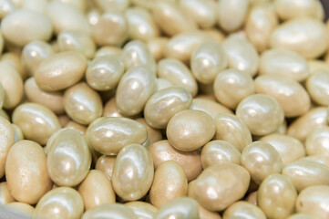 pile of candied almond dragees serves as a backdrop. Handmade nut candies in white chocolate