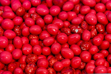 Hazelnut dragees in sugar glaze. Close-up of hazelnut candies. A background of a pile of nuts covered in bright red glaze