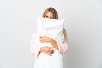 Young blonde woman isolated on white background in pajamas and holding a pillow