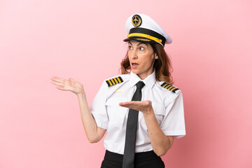 Airplane middle aged pilot woman isolated on pink background with surprise facial expression