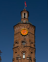 Historic water tower in Vinnytsia, Ukraine. Built in 1912, now a city symbol and museum. Photo taken on September 27, 2025. Blue sky, red flag, Roman numeral clock.