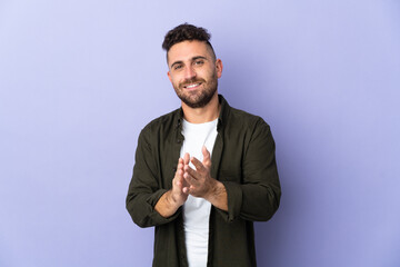 Caucasian man isolated on purple background applauding after presentation in a conference