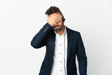 Telemarketer man working with a headset isolated on white background covering eyes by hands. Do not...