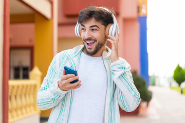 Handsome Arab man at outdoors listening music with a mobile and singing