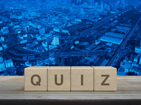 Quiz letter on wood block cubes on wooden table over modern city tower, street, expressway and skyscraper, Examination or test concept
