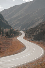 Curving roads navigate through majestic mountains, surrounded by natural beauty in a quiet, inviting environment perfect for exploration and adventure.